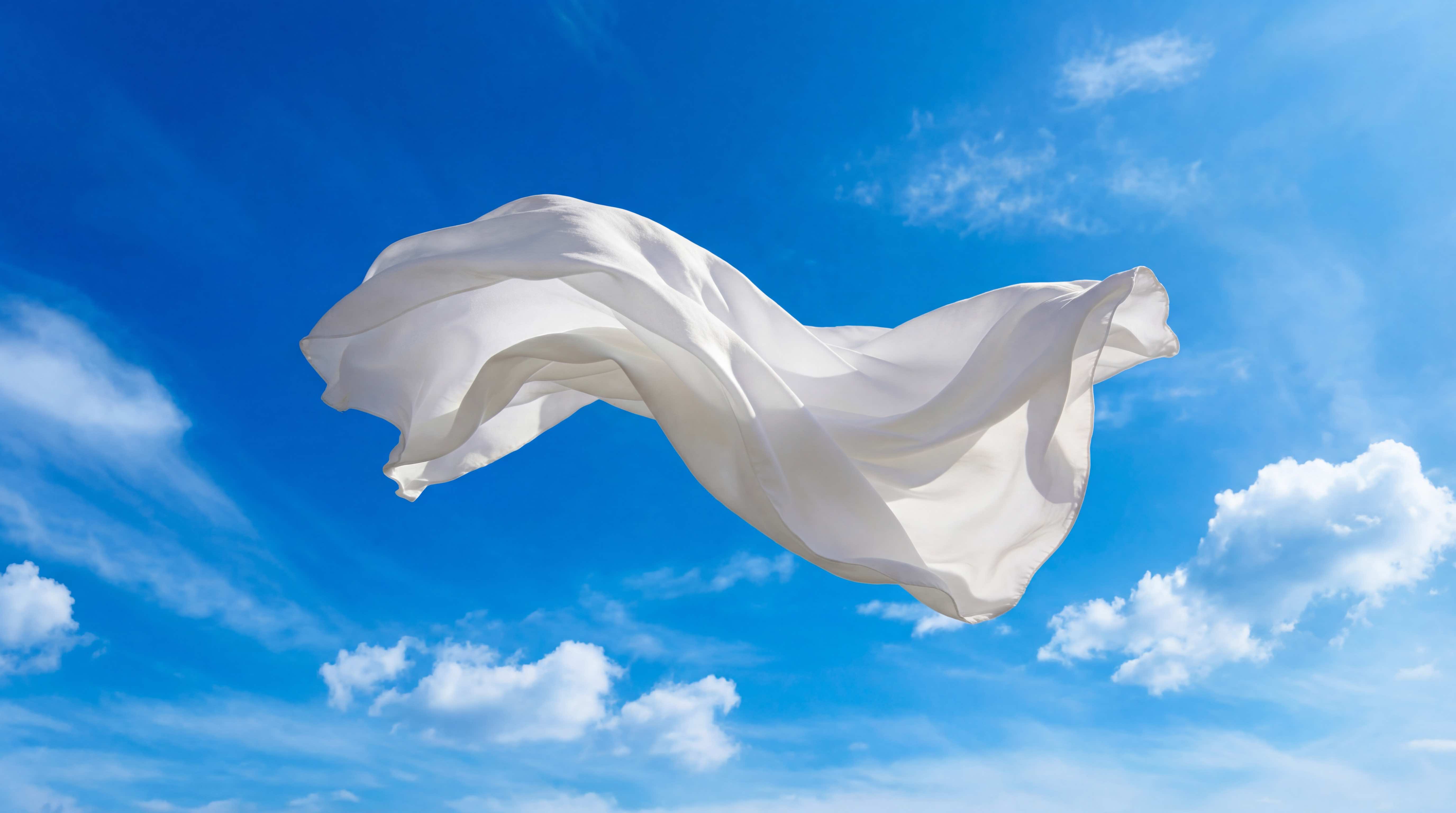 White fabric flowing in blue sky